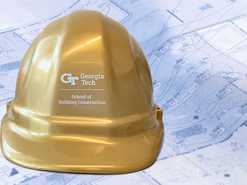 A graphic design of a School of Building Construction branded gold hard hat on top of blueprints.