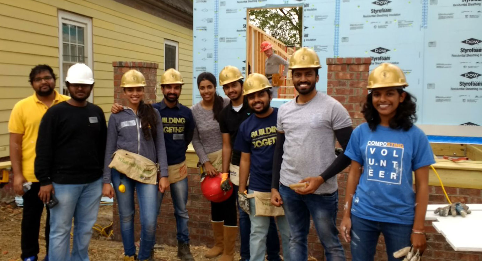 Student Construcation Association students pose for photo in front of Habitat Humanity construction project. 