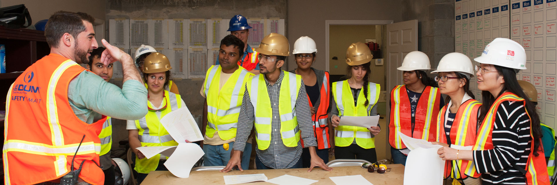 Students listen to a project manager speak inside a construction site. 