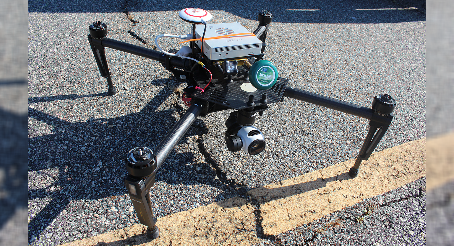Drone equipped with advanced sensors sitting over cracked pavement.