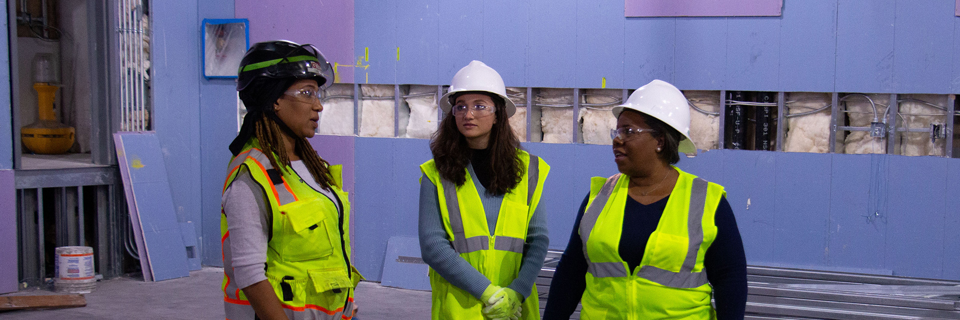 Three women in protective equipment on a construction site