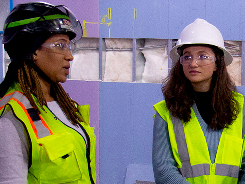 A student on a construction site learns from a foreman.
