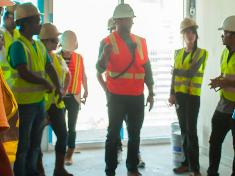 A group of students in PPE learn from a construction manager