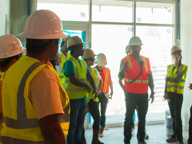 Students wear safety vests on a construction site.