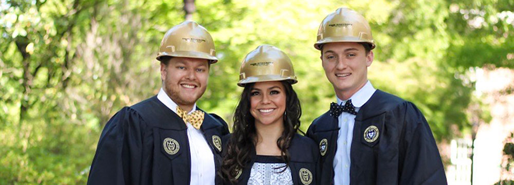 Undergraduates pose in gold hard hats and Georgia Tech graduation robes.