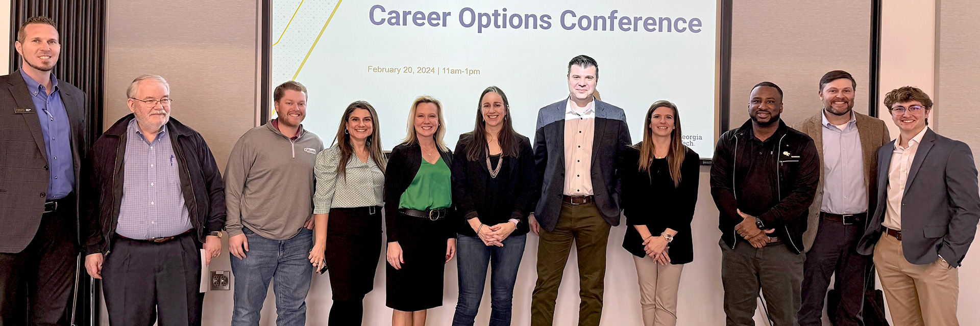 Corporate friends of the School of Building Construction pose for a photo in front of a projection screen that reads "Career Options Conference."