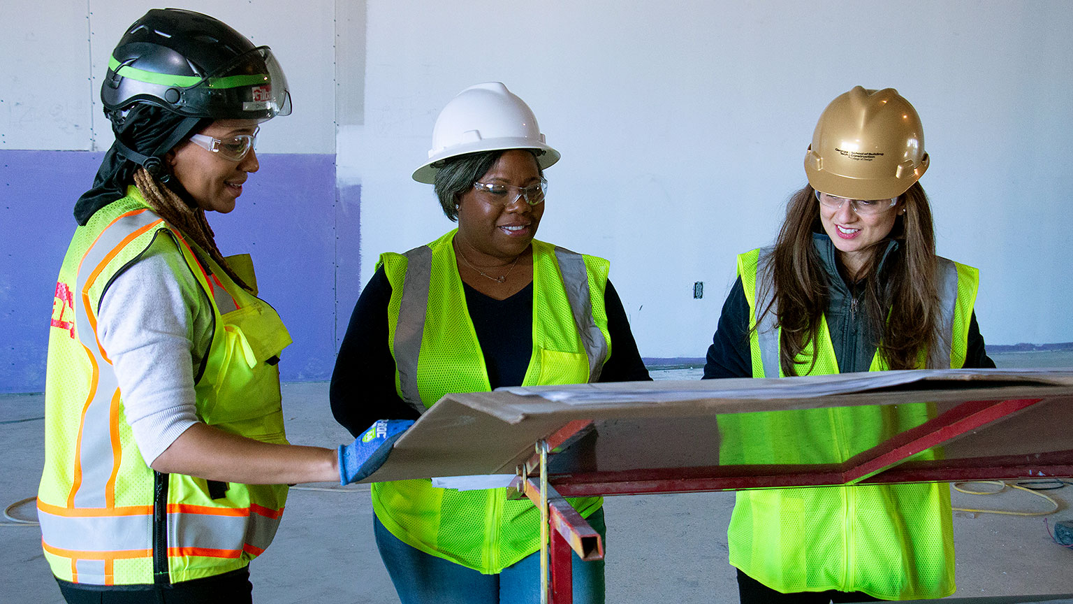 Christian Paul, Candace Washington, and Ece Erdogmus look at construction plans in the Student Center.